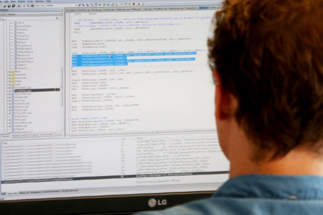 Ein Softwareentwickler sitzt vor einem Bildschirm, auf dem eine Entwicklungsumgebung zu sehen ist.